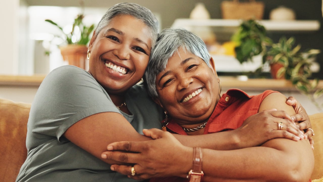 Seniors Helping Seniors photo of two people sitting together, smiling at the camera