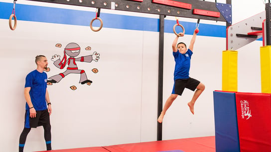 photo of a coach and student at USA Ninja Challenge. both are wearing blue shirts and black pants