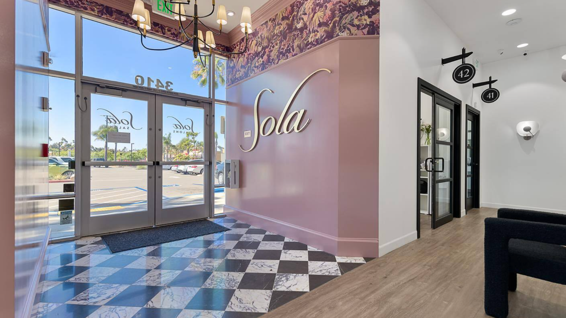 Photo of lobby of Sola Salons location with pink wall and floral wallpaper